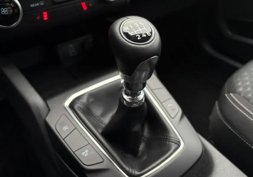 Le levier de vitesses manuel du Ford Kuga 2024 en cuir noir, vu de près au centre de la console.