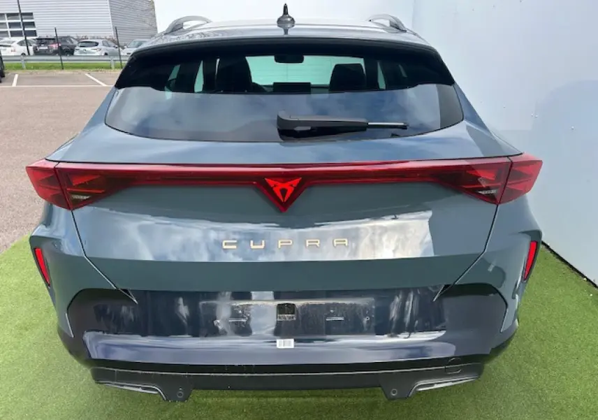 Vue arrière d'une CUPRA Formentor gris Fiord Metal avec bandeau lumineux rouge et logo CUPRA éclairé.