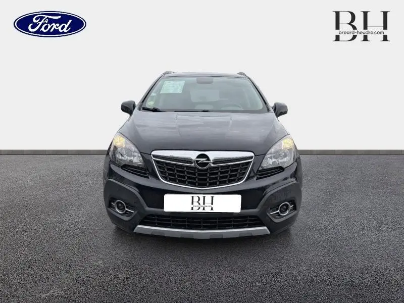 Vue frontale d'un Opel Mokka noir carbone 2016 avec calandre chromée et feux allumés sur fond neutre.