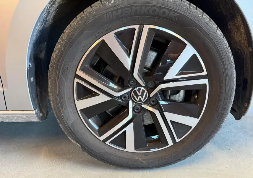 Gros plan sur la jante alliage noire et argentée du côté gauche d’un Volkswagen Touran gris 2025.