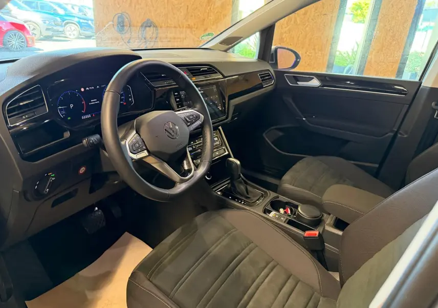 Vue intérieure côté conducteur du Volkswagen Touran 2025, volant cuir multifonctions et tableau de bord digital.