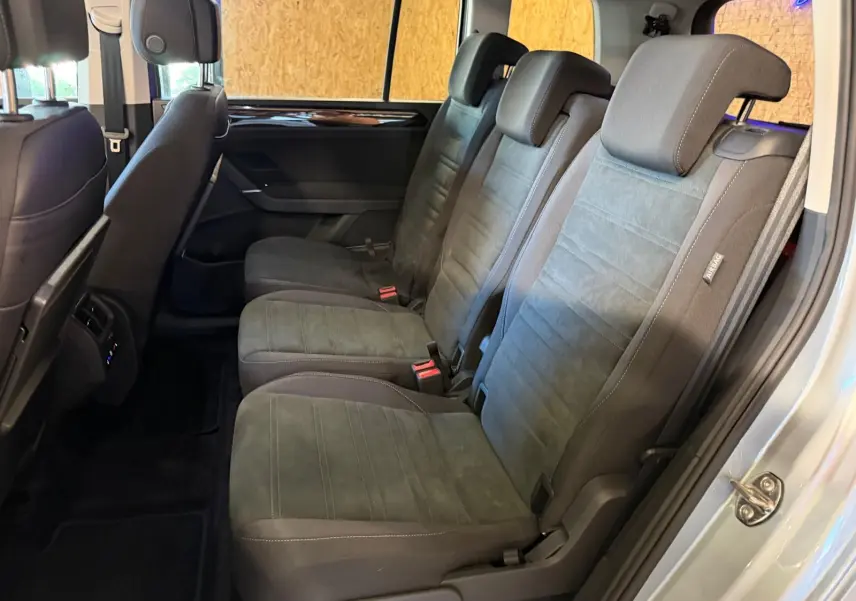 Vue latérale des sièges individuels arrière gris foncé du Volkswagen Touran 2025, avec habillage tissu et ceintures visibles.