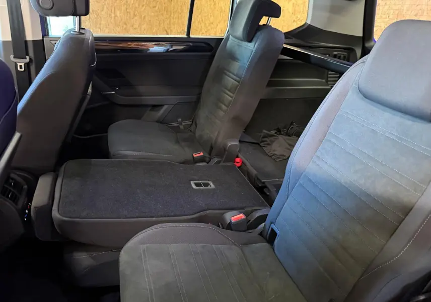 Vue intérieure côté droit sur les sièges noirs de la 2ème rangée du Volkswagen Touran gris 2025, avec siège central rabattable.