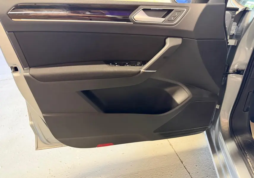 Vue intérieure de la porte avant gauche grise du Volkswagen Touran 2025 avec garniture noire et insert chromé.