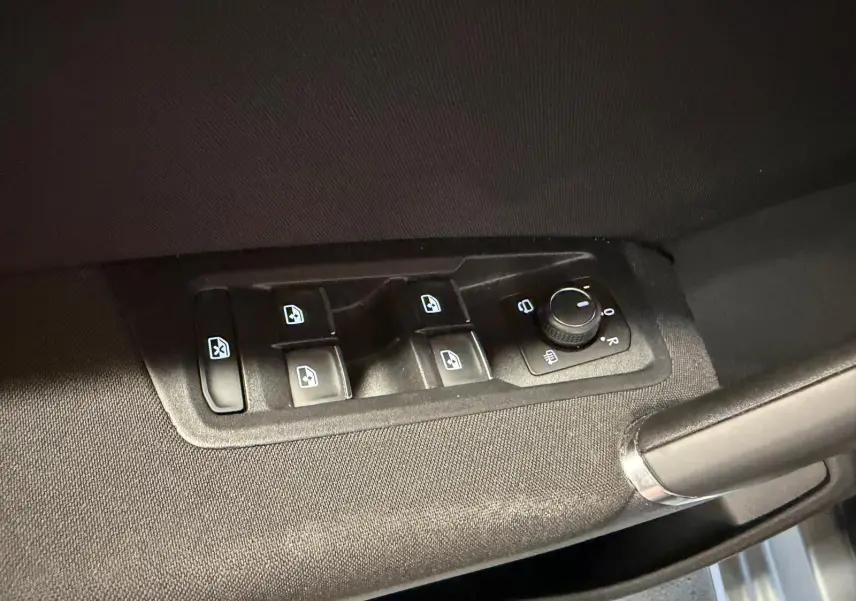 Commande des vitres électriques et réglage des rétroviseurs sur la porte côté conducteur d’un Volkswagen Touran gris.