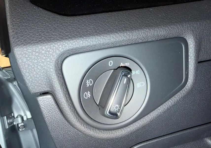 Gros plan sur le bouton de commande des phares dans un Volkswagen Touran gris, intérieur côté gauche.