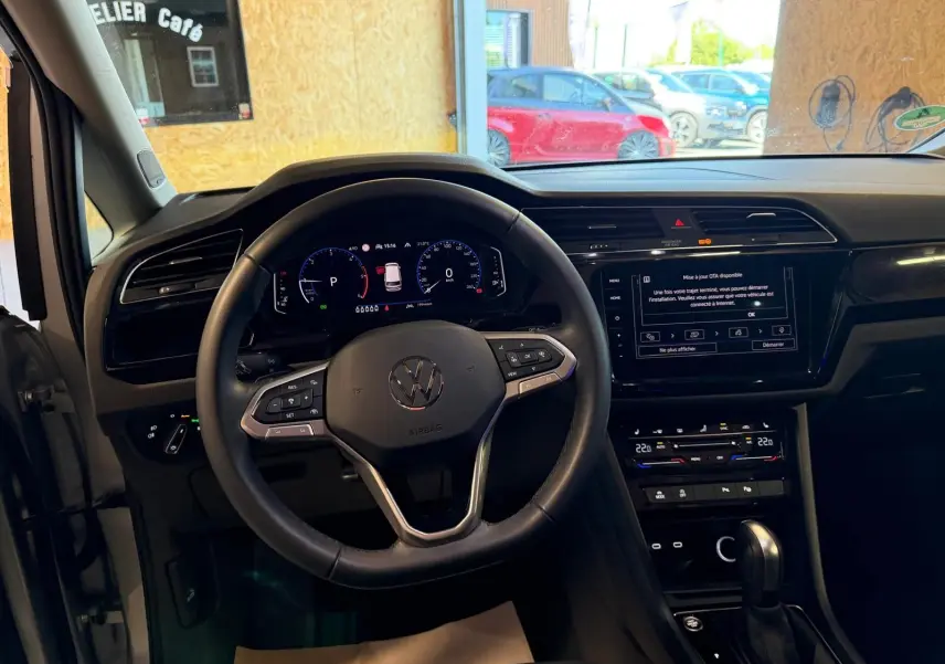 Vue intérieure centrée sur le volant cuir multifonctions et le tableau de bord numérique du Volkswagen Touran gris 2025.
