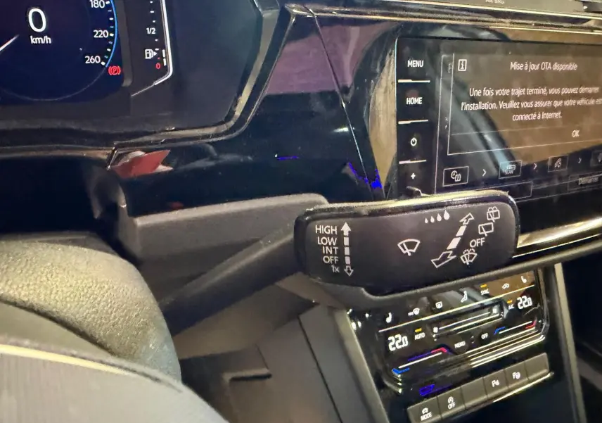 Vue intérieure rapprochée du tableau de bord noir du Volkswagen Touran 2025, avec commandes d’essuie-glace et écran tactile.