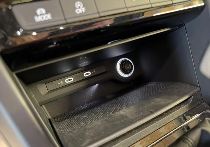 Gros plan sur la console centrale noire du Volkswagen Touran 2025, montrant deux ports USB-C et une prise 12V éclairée.