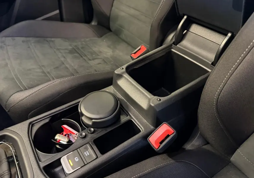 Vue rapprochée de la console centrale noire entre les sièges avant gris foncé du Volkswagen Touran 2025.