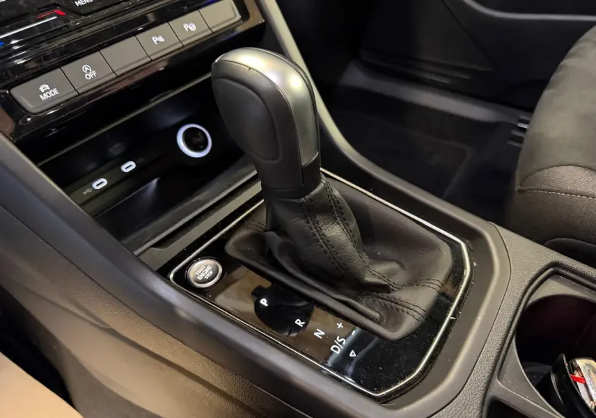 Gros plan sur la commande de la boîte automatique noire et cuir dans l’habitacle du Volkswagen Touran gris.