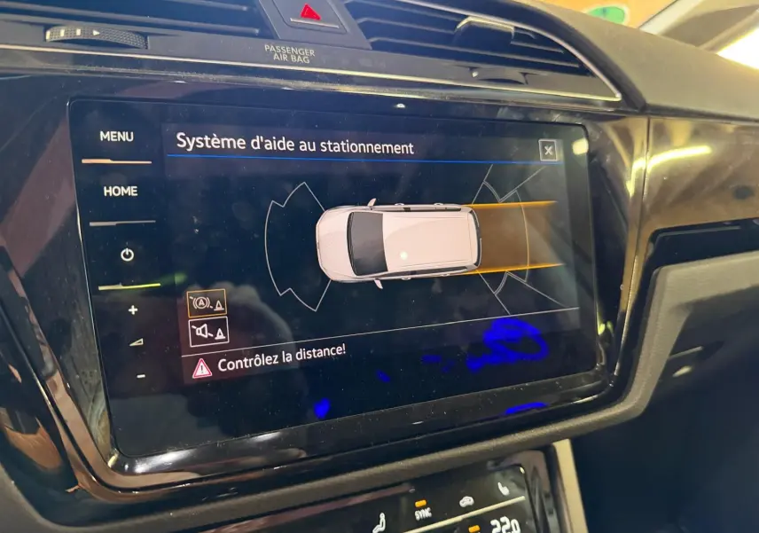 Écran tactile intérieur du Volkswagen Touran 2025 affichant l'aide au stationnement avec alertes de distance.