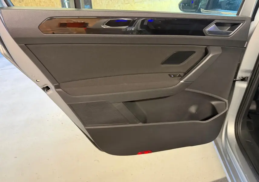 Vue intérieure de la porte arrière gauche gris clair du Volkswagen Touran 2025 avec garniture noire et insert brillant.