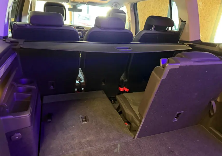 Vue arrière intérieure du Volkswagen Touran gris 2025, montrant les sièges rabattables et la tablette de coffre.