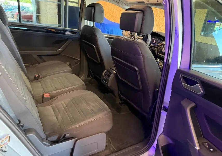 Vue intérieure côté gauche de la 2ème rangée du Volkswagen Touran gris 2025, sièges individuels et rangements visibles.