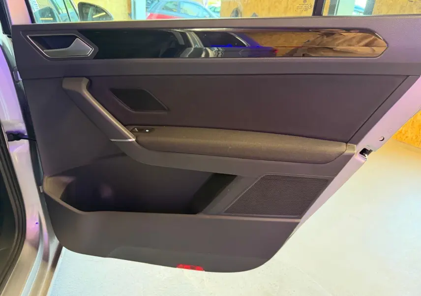 Vue intérieure côté gauche de la porte avant grise du Volkswagen Touran 2025 avec insert décoratif noir brillant.