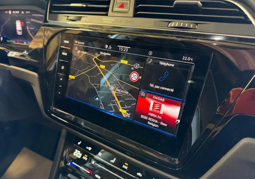Vue rapprochée de l'écran tactile central du Volkswagen Touran 2025, affichant navigation et radio FM/DAB.