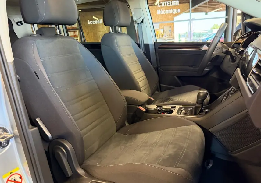 Vue intérieure côté conducteur du Volkswagen Touran gris 2025, mettant en valeur les sièges avant en tissu et alcantara.