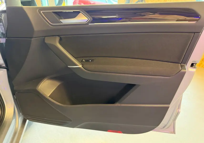 Vue rapprochée de la porte avant gauche grise du Volkswagen Touran 2025 avec garniture noire et insert chromé.