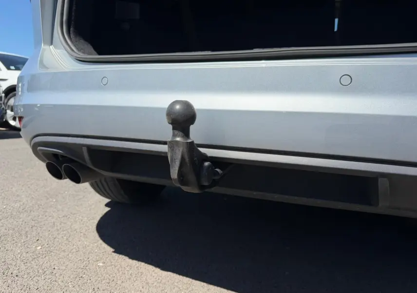 Gros plan sur l'attelage arrière noir du Volkswagen Touran gris 3/4 arrière avec double sortie d'échappement visible.