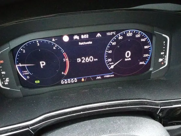 Vue rapprochée du tableau de bord numérique du Volkswagen Touran gris, affichant la vitesse à 0 km/h et l'autonomie à 260 km.