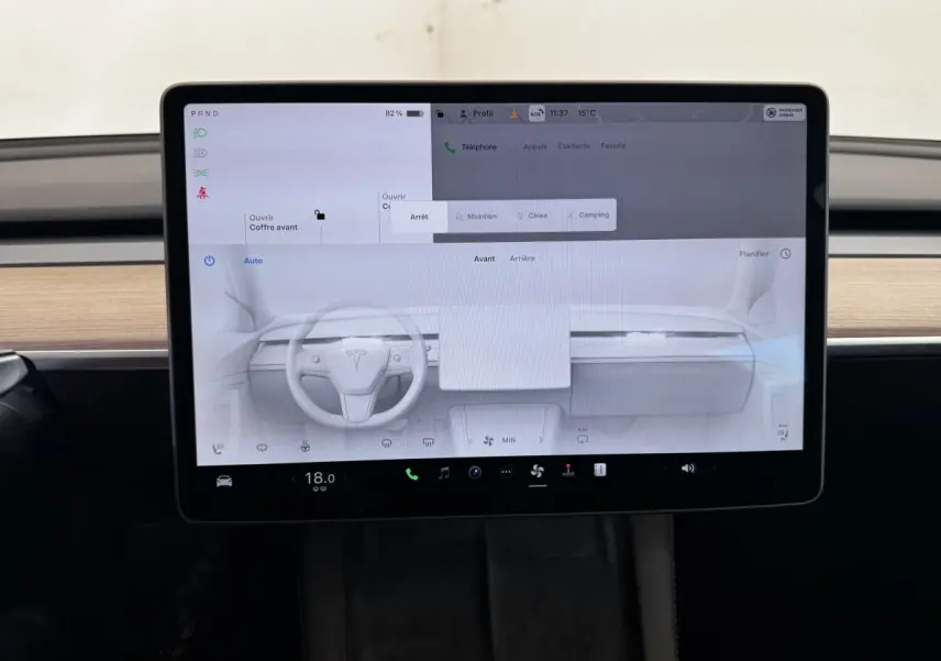 Écran tactile central allumé dans l’habitacle d’une Tesla Model 3 noire, vue frontale rapprochée.