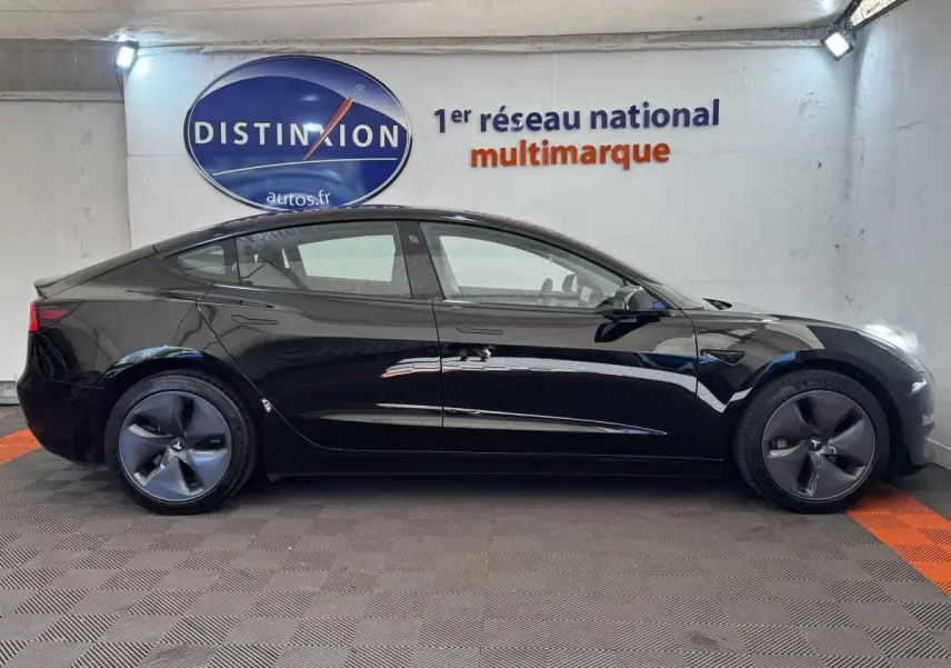 Profil latéral droit d'une Tesla Model 3 Grande Autonomie noire, avec jantes aérodynamiques et poignées affleurantes.