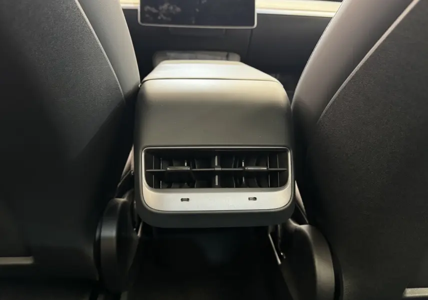 Gros plan sur la console centrale arrière noire de la Tesla Model 3 2023 avec bouches d’aération et ports USB-C.