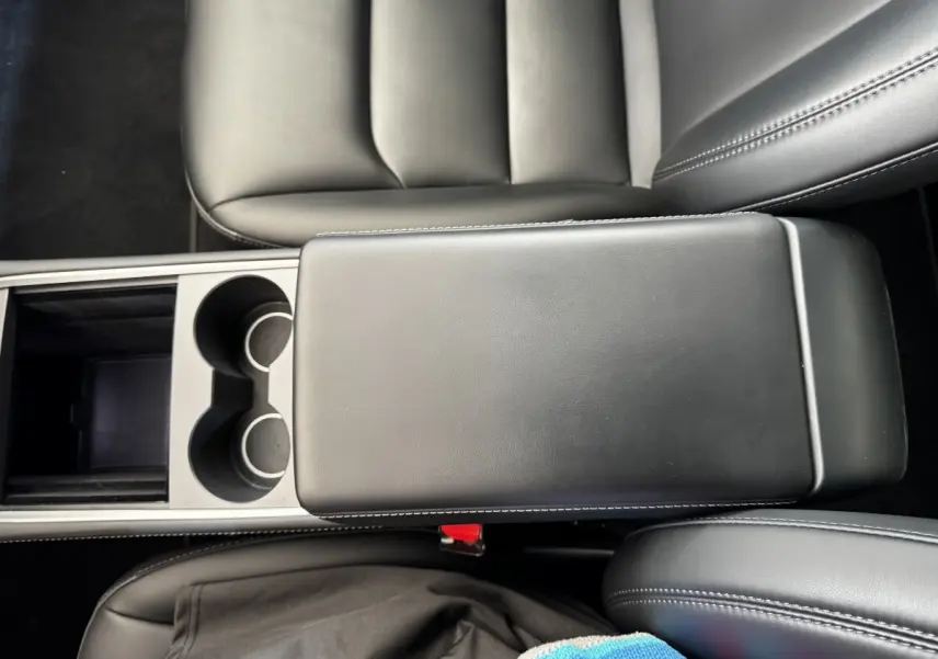 Vue plongeante sur l'accoudoir central noir et les sièges en cuir noir de la Tesla Model 3 Grande Autonomie 2023.