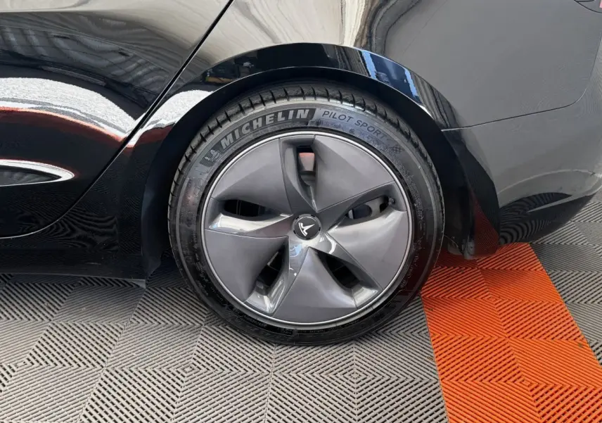 Gros plan sur la roue arrière droite noire d'une Tesla Model 3 2023 avec jante aérodynamique et pneu Michelin Pilot Sport.