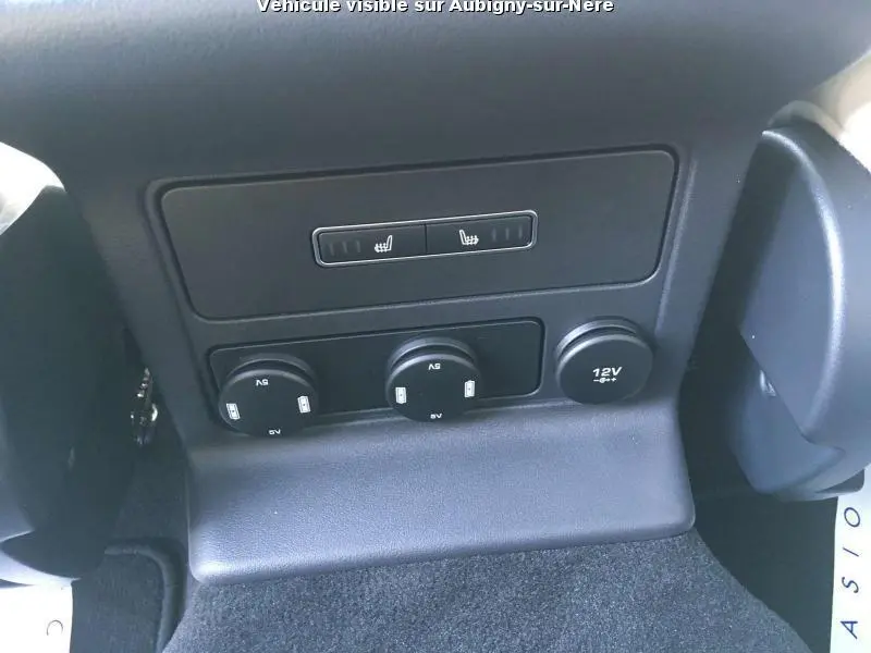 Vue rapprochée des commandes de sièges chauffants et prises 12V à l'arrière d'un Jaguar F-PACE noir de 2018.
