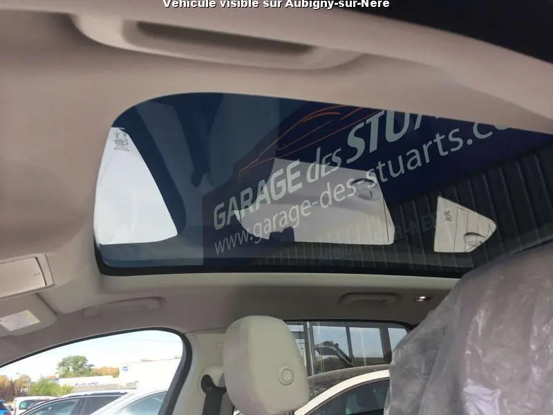 Toit vitré panoramique vu de l'intérieur côté avant gauche d'une Jaguar F-PACE noire, sièges clairs visibles.