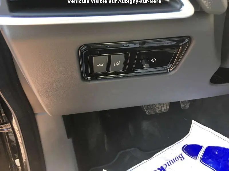 Détail des commandes sous le tableau de bord côté conducteur du Jaguar F-PACE noir, avec pédales visibles.