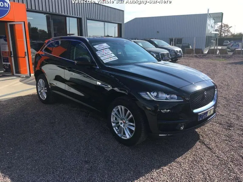 Jaguar F-PACE noir vue 3/4 avant droit, jantes argentées, stationnée devant un bâtiment commercial.