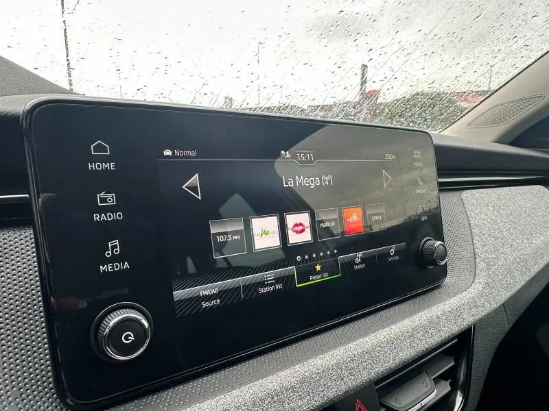 Écran tactile central de la Skoda Scala blanc cristal, vue intérieure côté passager sous pluie.