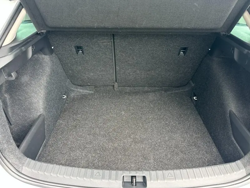 Coffre ouvert vu de face de la Skoda Scala blanc cristal, espace de chargement tapissé gris foncé.