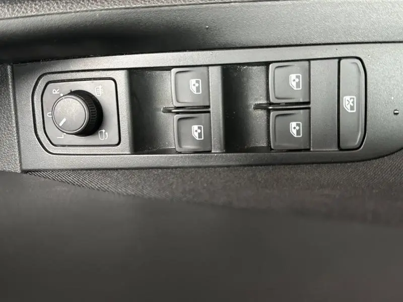 Gros plan sur les commandes de réglage des rétroviseurs et des vitres électriques côté conducteur du Skoda Scala blanc cristal.