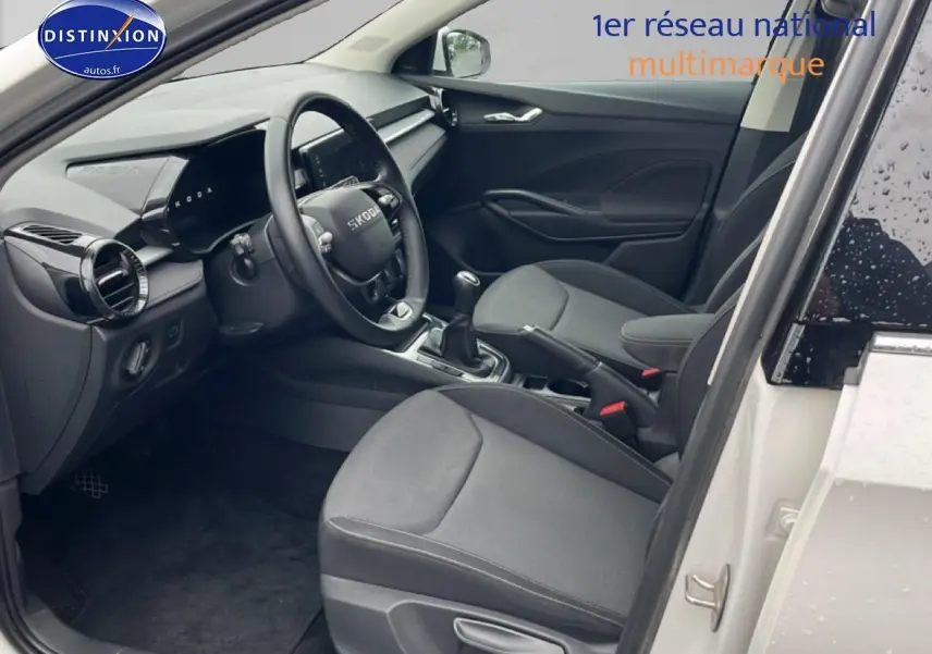 Intérieur avant droit d’une Skoda Fabia blanche 2025, volant cuir multifonction et sièges tissu gris.