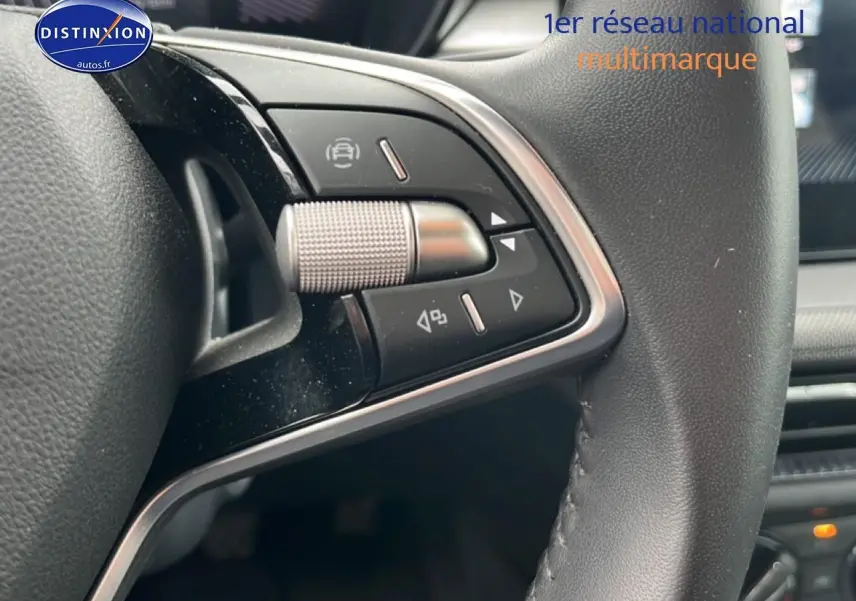 Gros plan sur les commandes multifonctions en cuir du volant de la Skoda Fabia blanche, intérieur moderne.