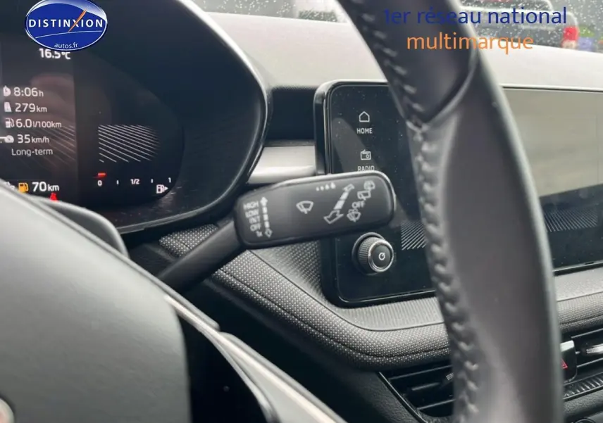 Vue rapprochée de l'intérieur de la Skoda Fabia blanche 2025, tableau de bord et volant multifonction en cuir visibles.