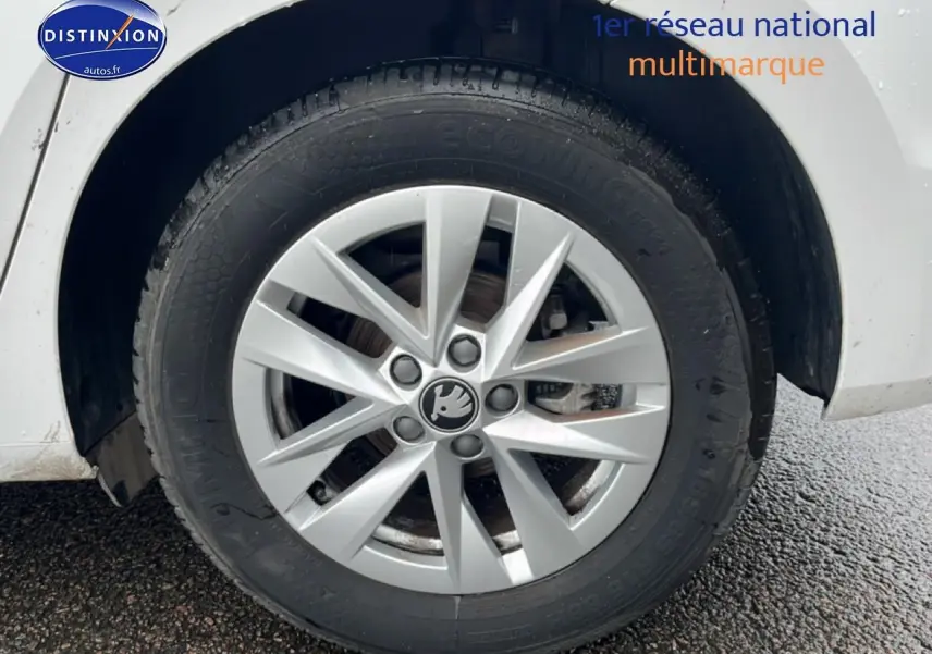 Gros plan sur la roue avant gauche blanche d'une Skoda Fabia 2025 avec jante alliage et logo central visible.