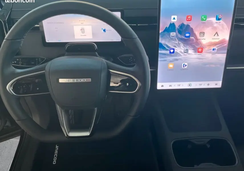 Vue intérieure frontale du volant noir JAECOO J7 1.5 TGDI 279ch avec grand écran tactile vertical lumineux.