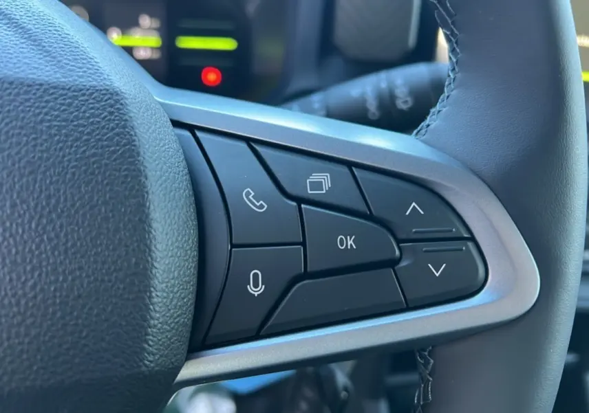Gros plan sur les commandes au volant du Dacia Duster 2025, version Mild Hybrid 130 4x4 Expression, cuir noir et boutons multifonctions.