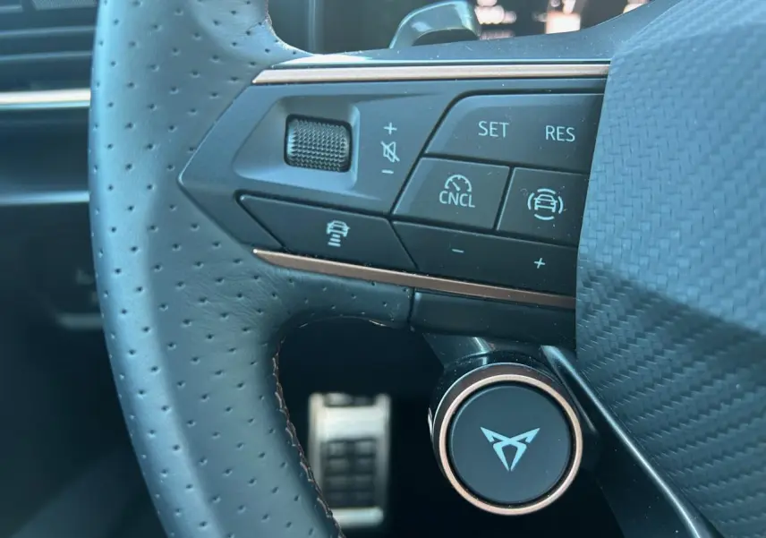 Gros plan sur le volant perforé noir du CUPRA Formentor 2025 avec commandes multifonctions et logo central distinctif.