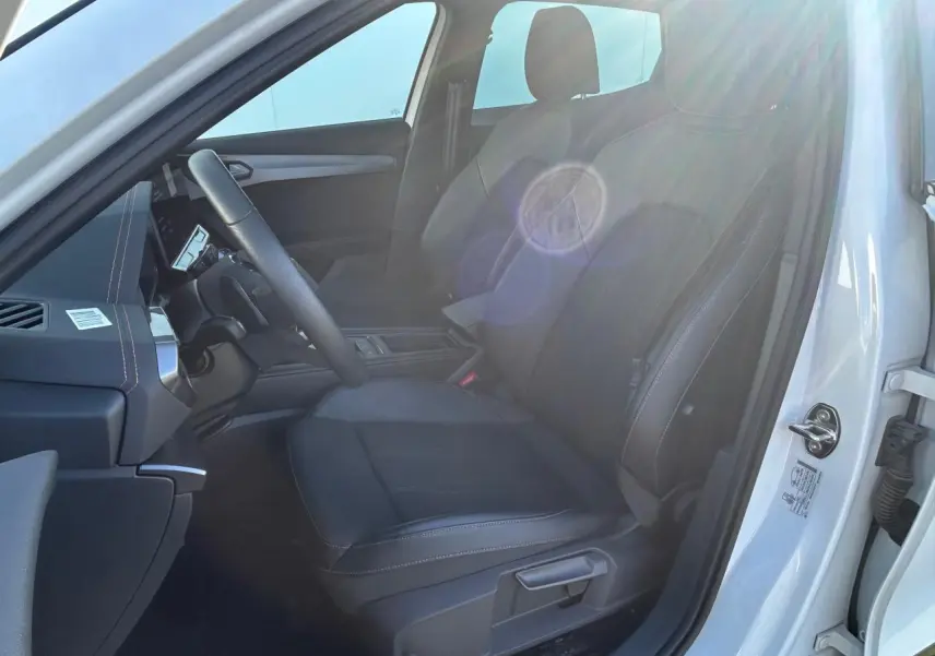 Vue intérieure côté conducteur du CUPRA Formentor blanc neige 2025, siège avant en tissu noir avec surpiqûres contrastantes.