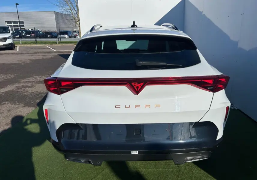 Vue arrière d'un CUPRA Formentor blanc neige avec bandeau lumineux rouge et diffuseur noir contrastant.