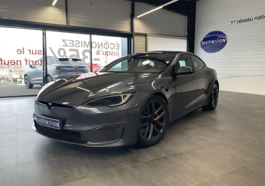 Tesla Model S Plaid gris foncé vue 3/4 avant droit en intérieur avec jantes noires et étriers rouges visibles.