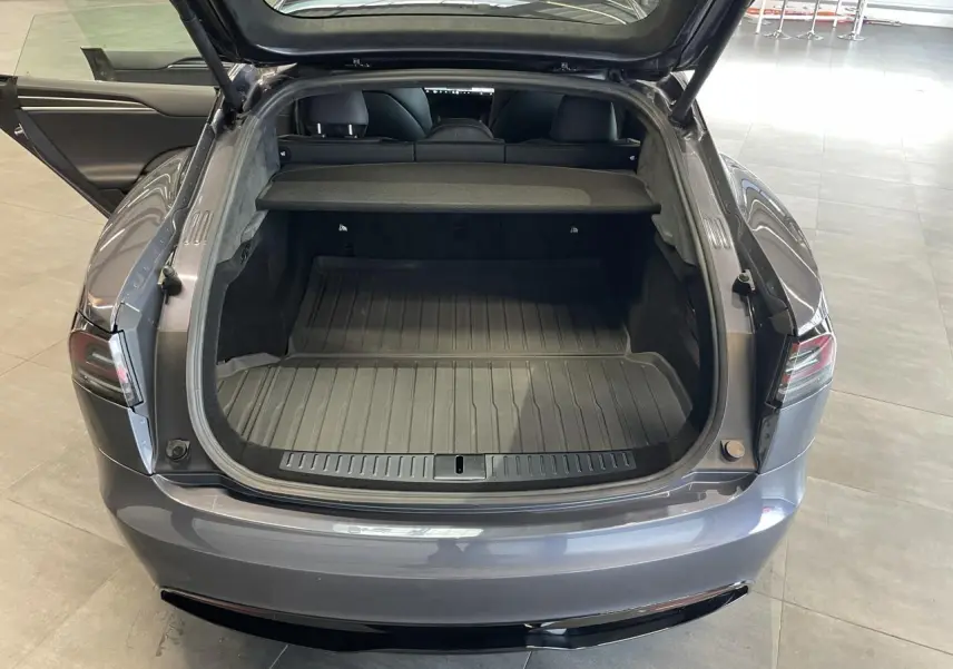 Vue arrière ouverte du coffre d'une Tesla Model S Plaid gris foncé, montrant l'espace de chargement et l'intérieur noir.