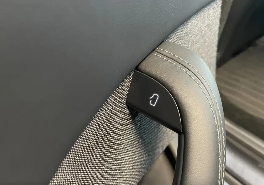 Détail de la poignée intérieure grise avec bouton de déverrouillage sur porte côté gauche d’une Tesla Model S Plaid 2023.