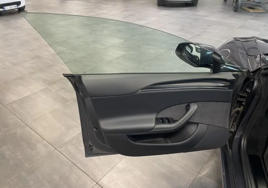 Vue de la porte avant gauche ouverte d'une Tesla Model S Plaid 2023 gris foncé, intérieur noir avec inserts carbone.